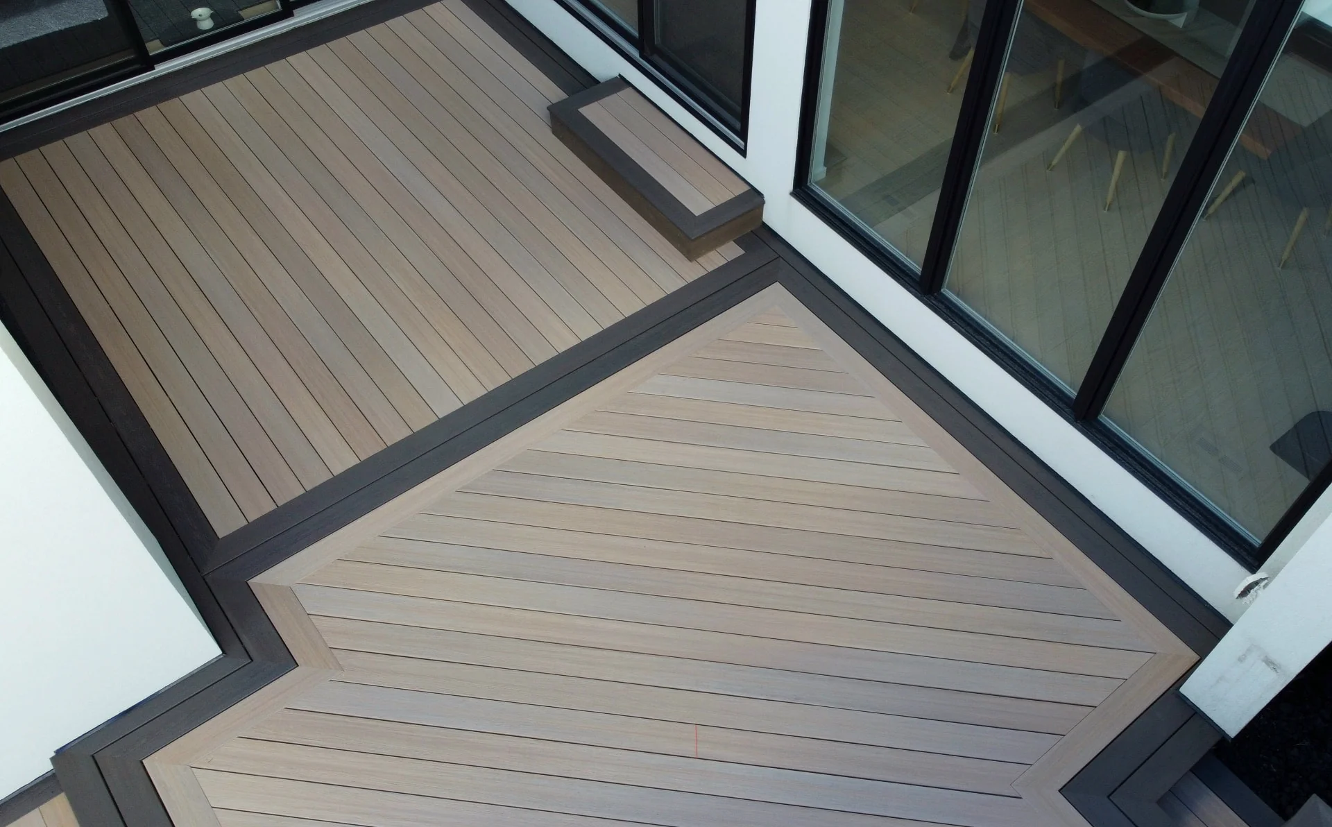 Composite deck with dark border and herringbone inlay built by D3 Decks & Fences