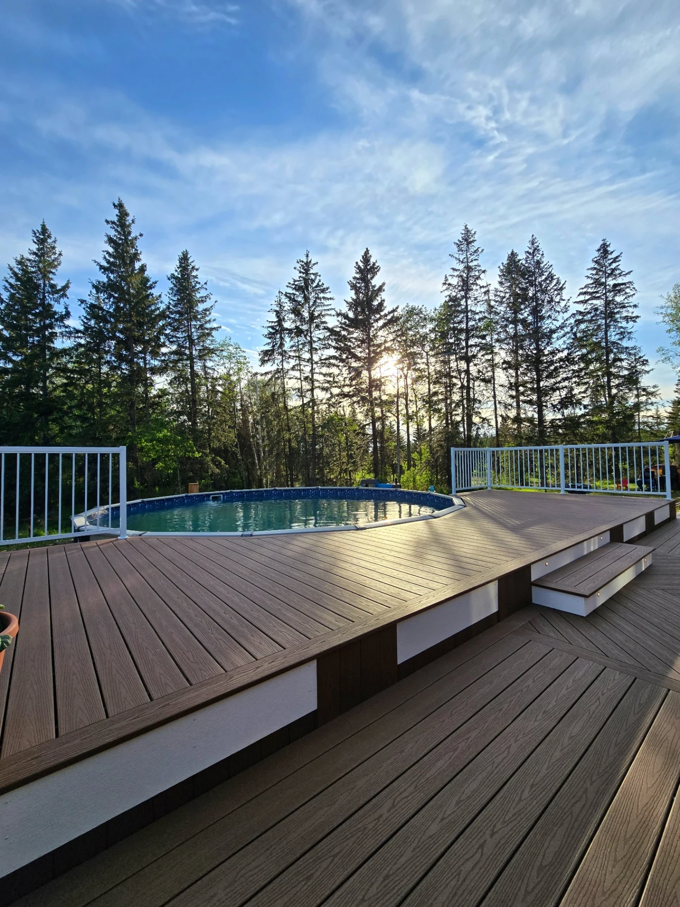 Composite pool deck at sunset surrounded by trees
